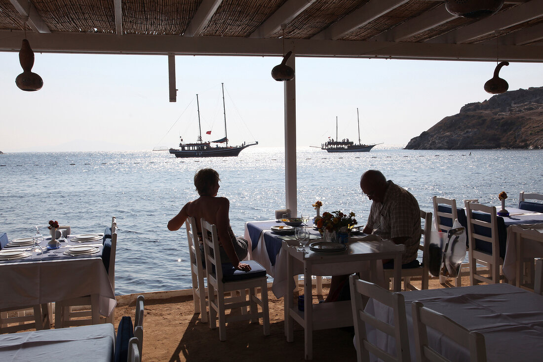 People sitting at Mimoza Restaurant near sea in Gumusluk, Aegean Region, Turkey