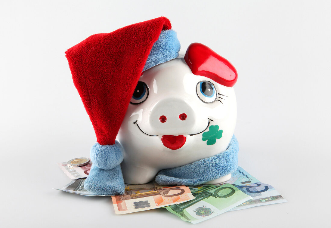 Piggy bank with hat, scarf and money on white background