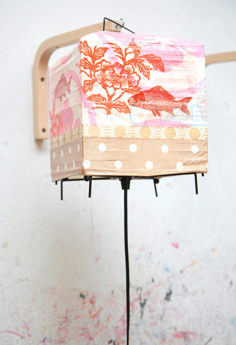 Close-up of person painting colourful lantern with flower and fish motif