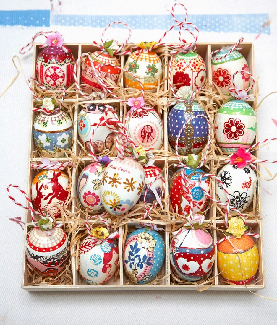 Colourfully painted Easter eggs in a seedling tray lined with straw