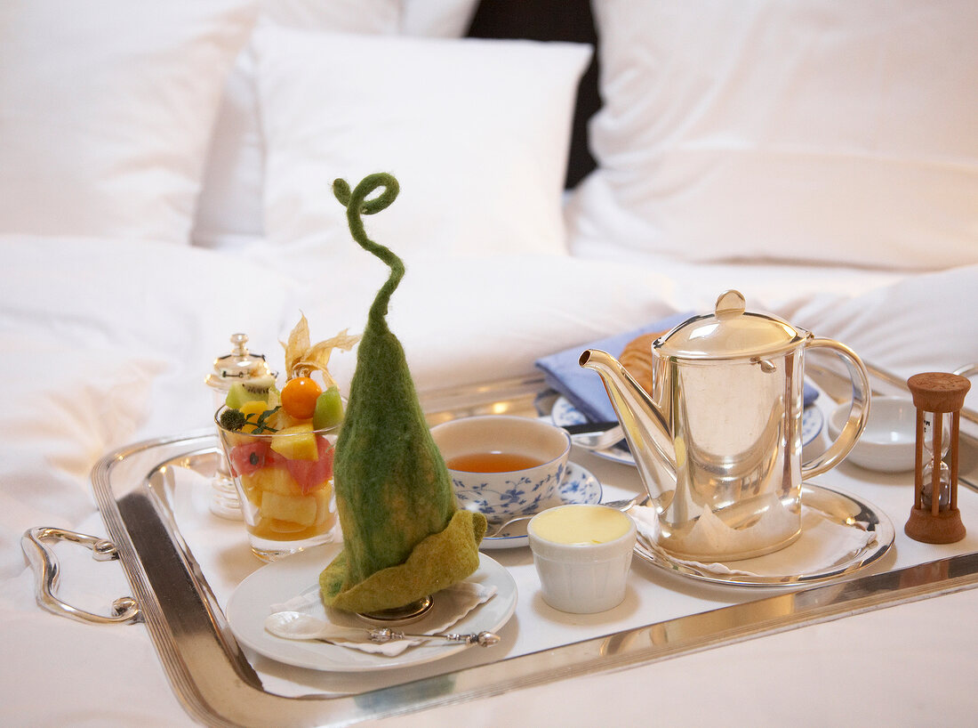Hotelzimmer: Frühstückstablett auf dem Bett mit Obstsalat im Glas