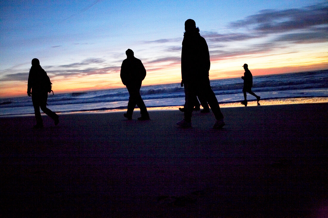 People walking on beach at sunset, Sylt, Germany
