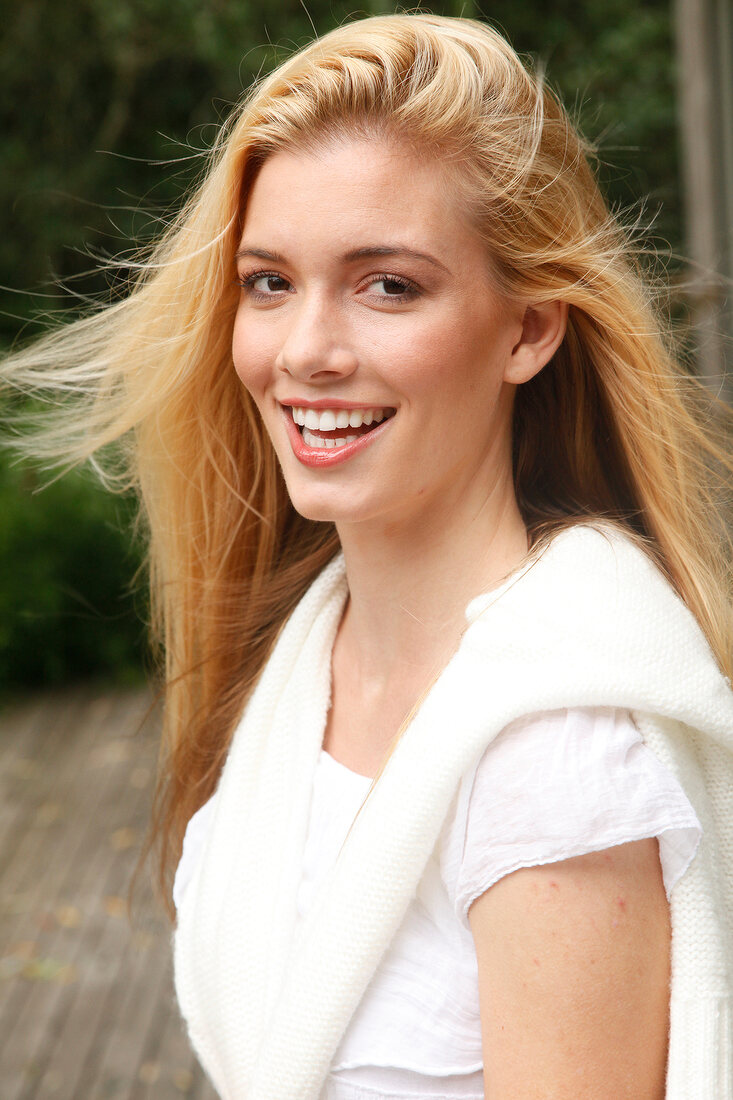 Portrait of beautiful blonde woman with long hair wearing white sweater, smiling