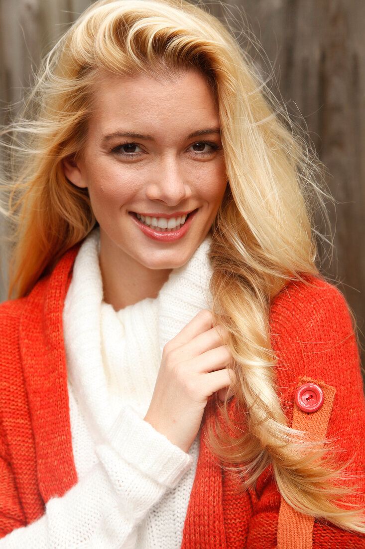 Portrait of beautiful blonde woman with long hair in white and orange cardigan, smiling