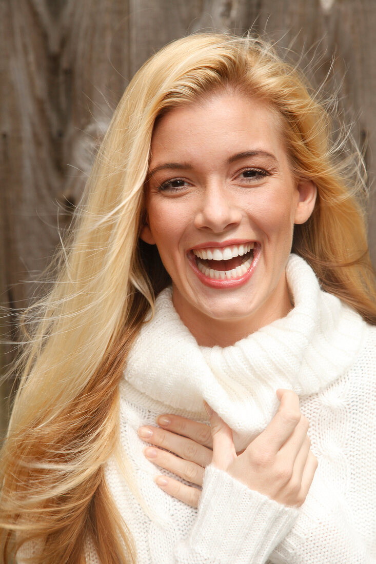 Portrait of beautiful blonde woman with long hair in white turtleneck sweater, smiling