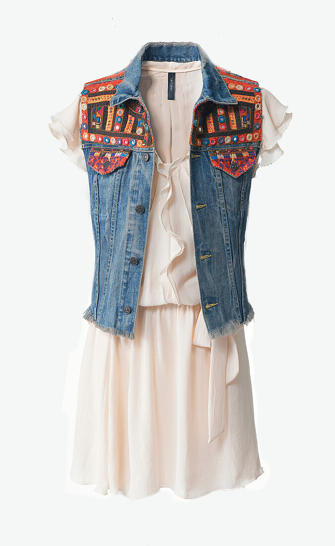 Embroidered denim vest over white dress against white background