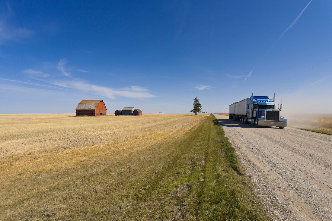 View of farmer house, landscape and trucks on road, Saskatchewan, Canada