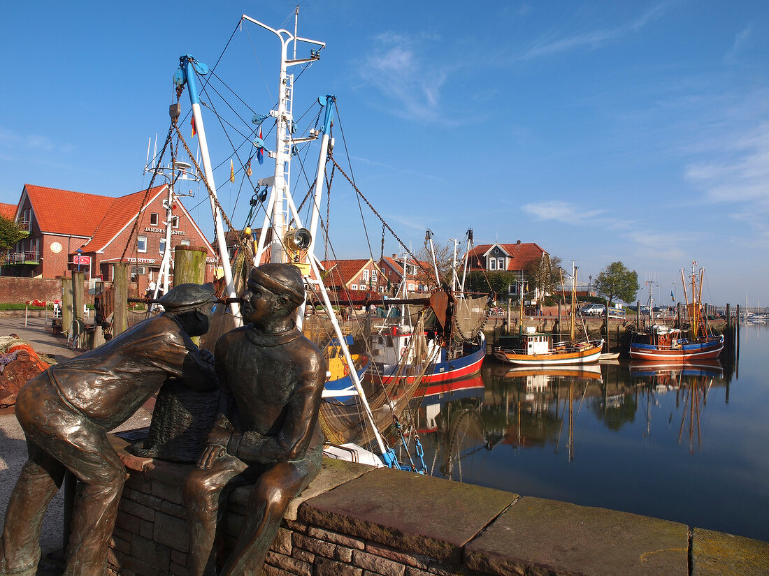 View of bronze monument and sailboats at harbour, Neuharlingersie, Saxony, Germany