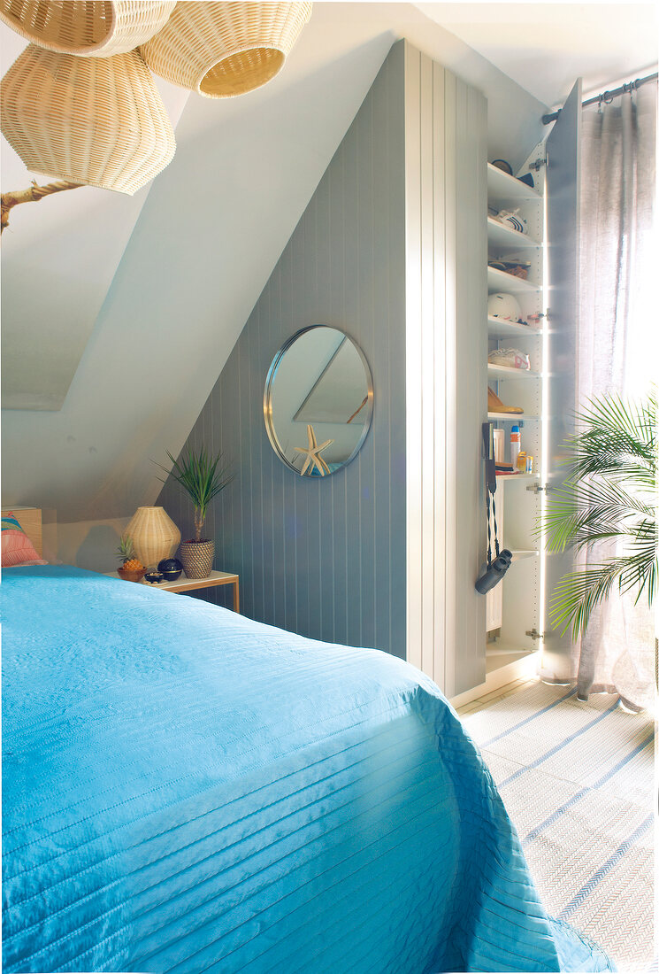 Bedroom with closet, pitched roof and round mirror on wall