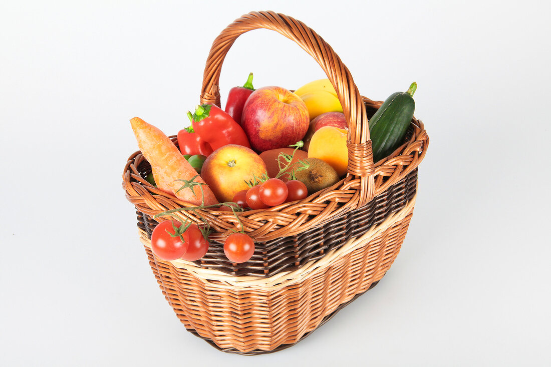 Basket of fruit and vegetables on white background
