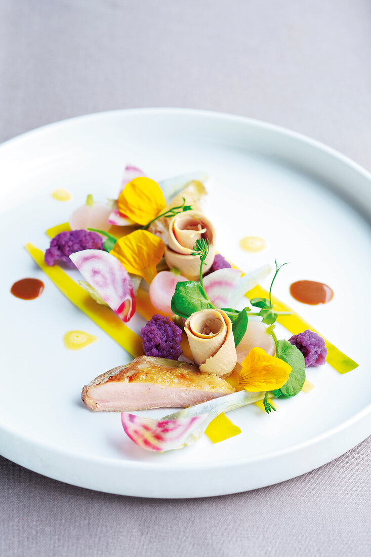 Close-up of quail meat with flowers and purple puree on plate