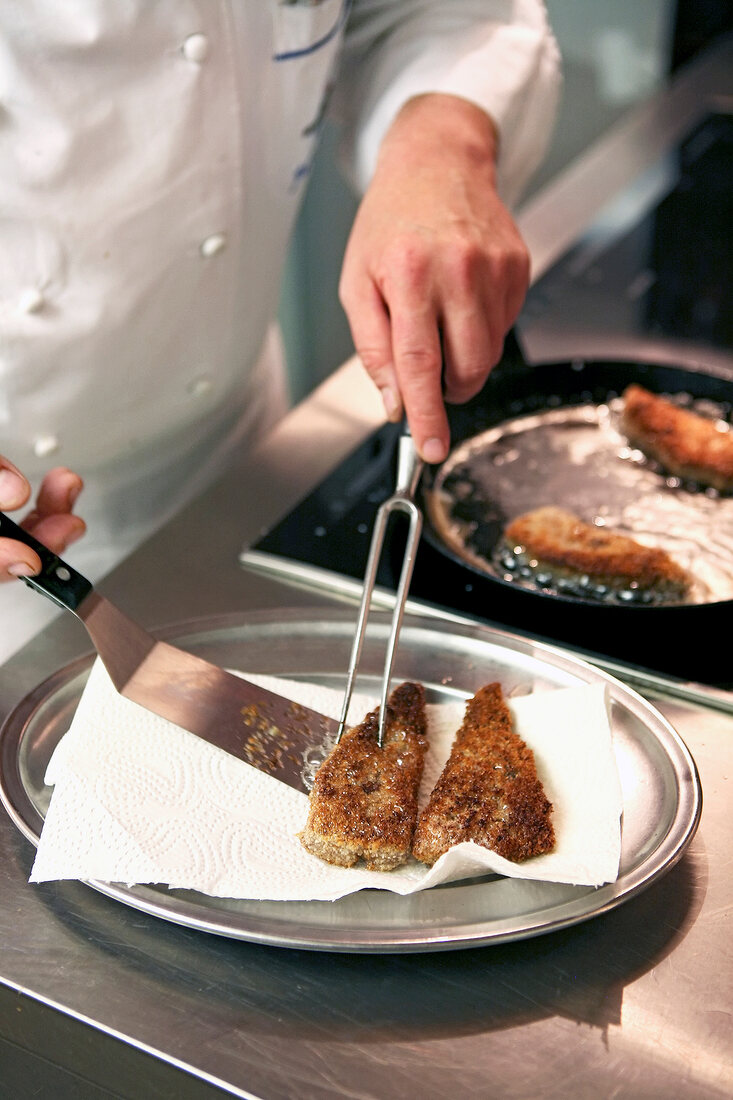 Chef placing fried beef liver slices on plate