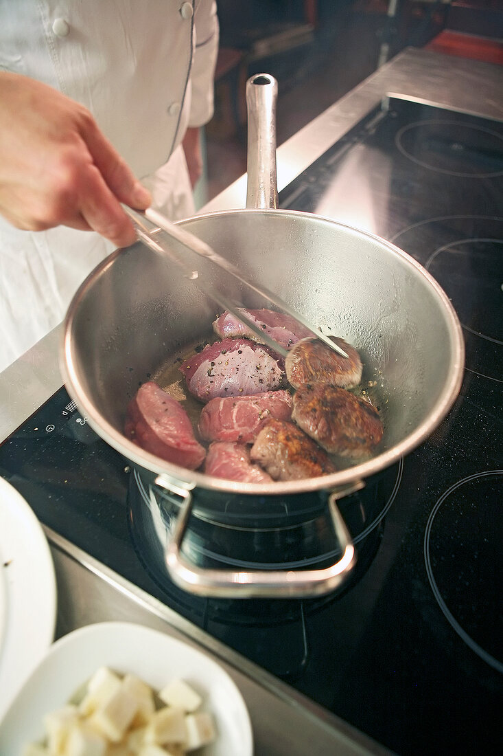 Pork cheeks being braised in pan