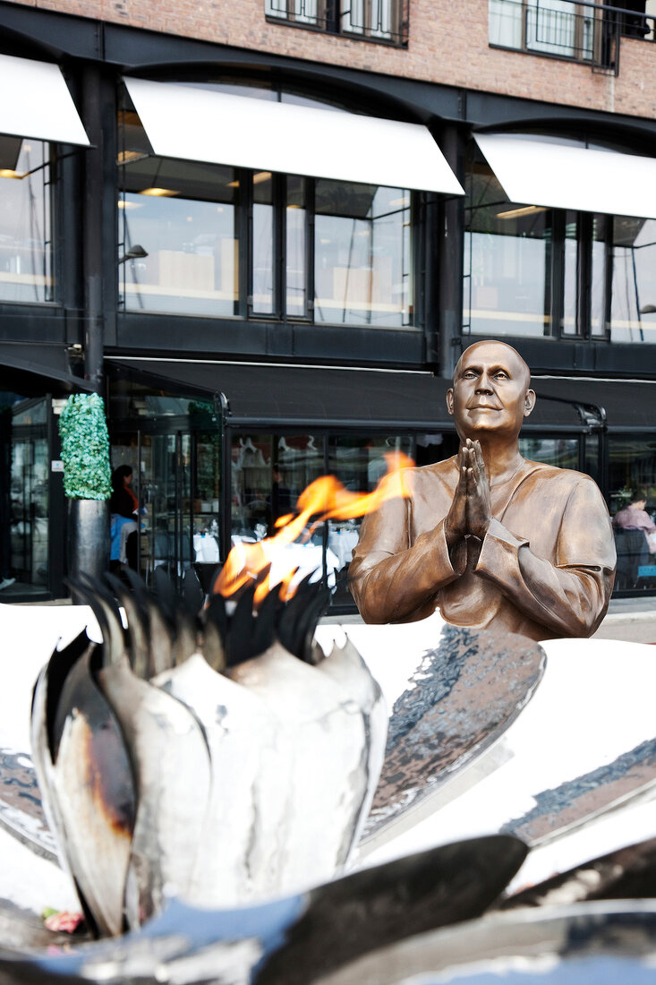 Burning torch with statue in praying position in Oslo, Norway