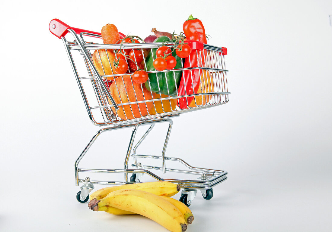 Shopping cart with vegetables and fruits on white background