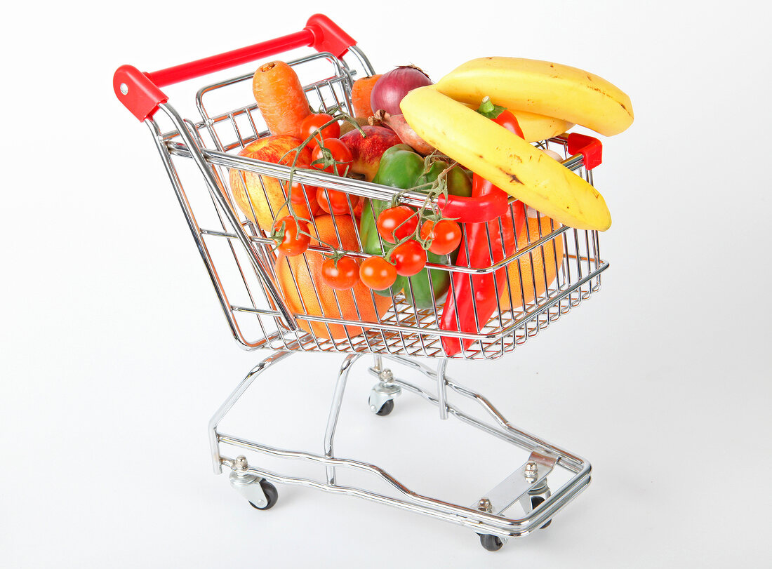 Shopping cart with vegetables and fruits on white background