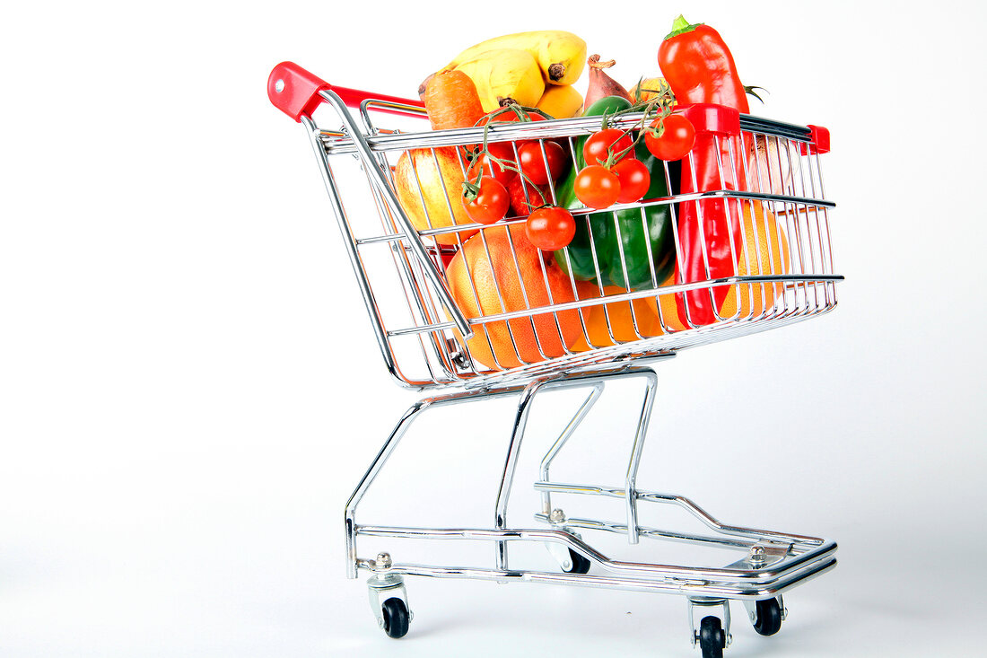 Shopping cart with vegetables and fruits on white background