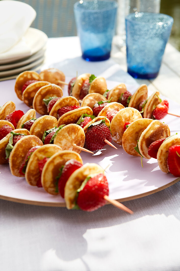 Mini pancakes with strawberries in skewers on plate