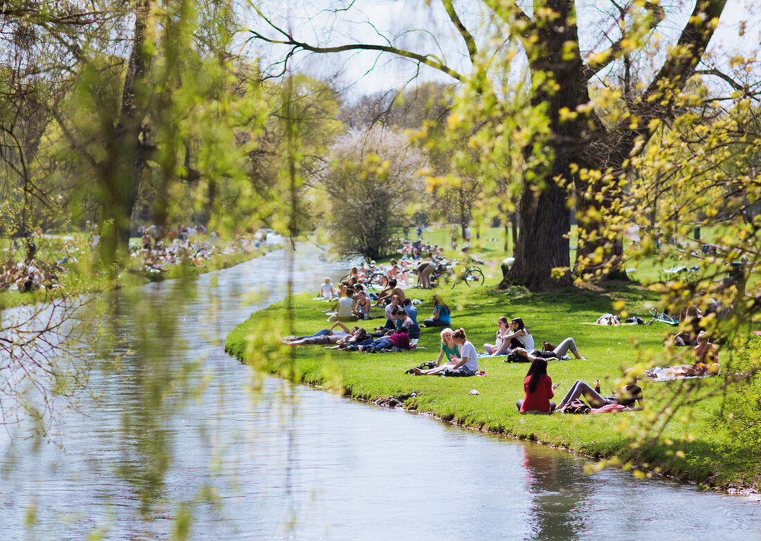 People relaxing in park beside Eisbach, Munich, Germany