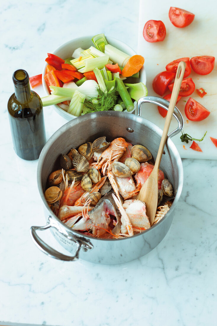 Bouillabaisse with lobster in pot next to chopped vegetables
