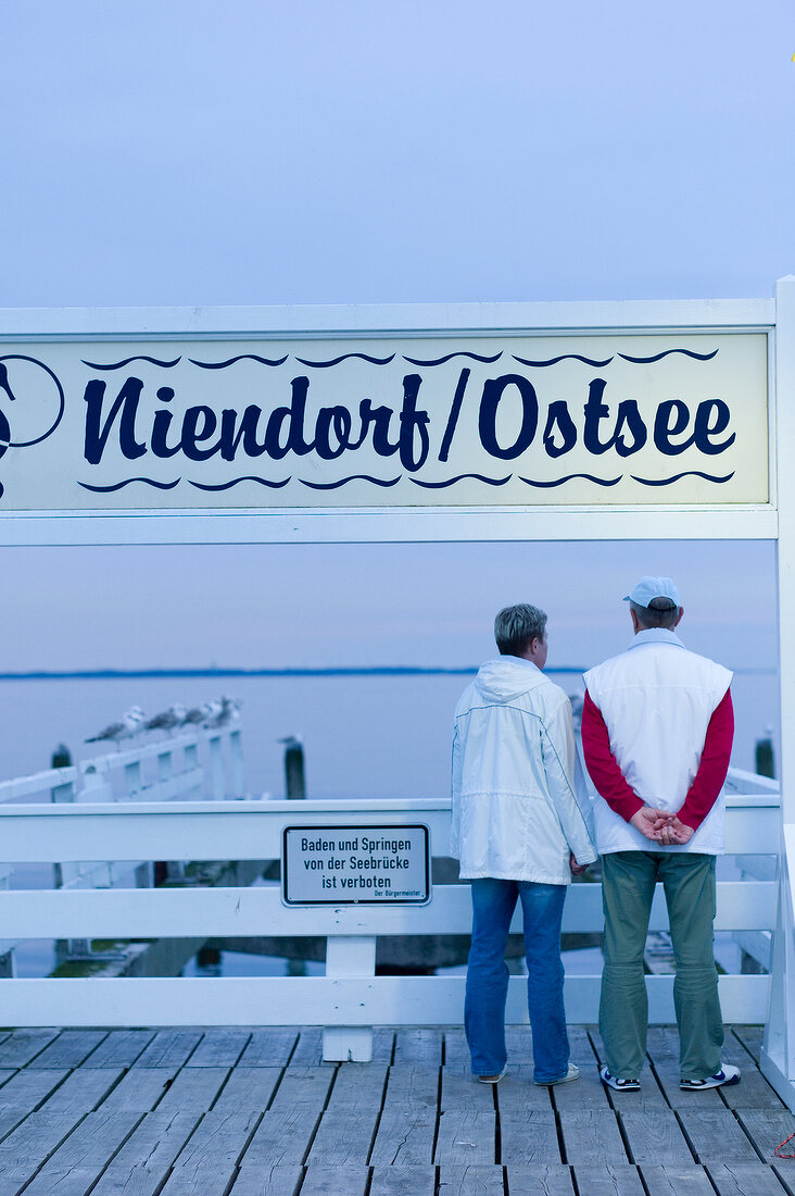 Rear view of two people standing on Niendorf harbour, Schleswig Holstein, Germany