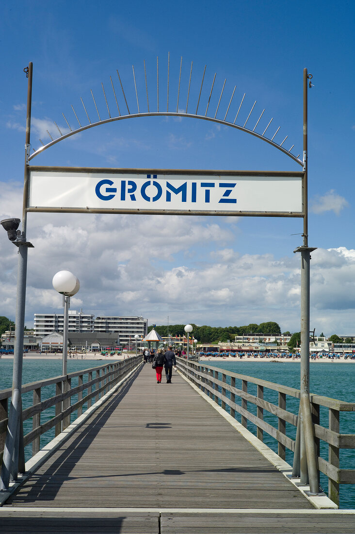 Rear view of couple walking through Gromitz bridge, Schleswig Holstein, Germany
