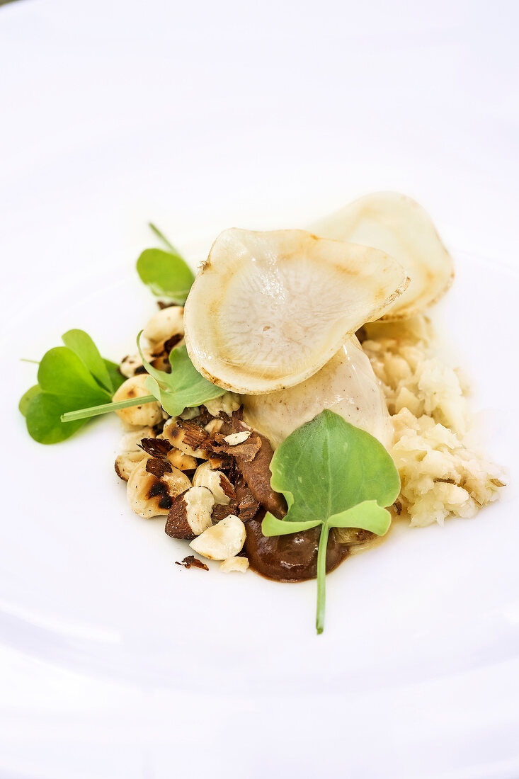 Close-up of hazelnuts, sorrel shield and root parsley on plate