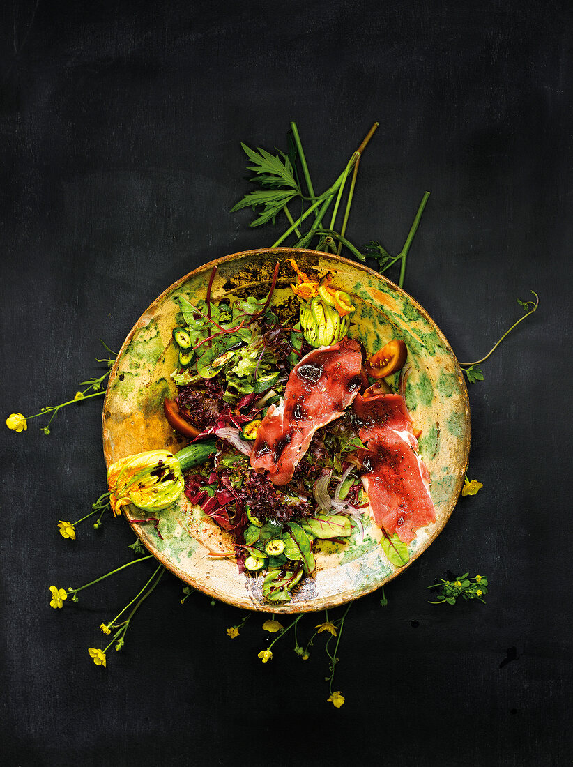 Salad with zucchini flowers and balsamic vinegar on serving dish