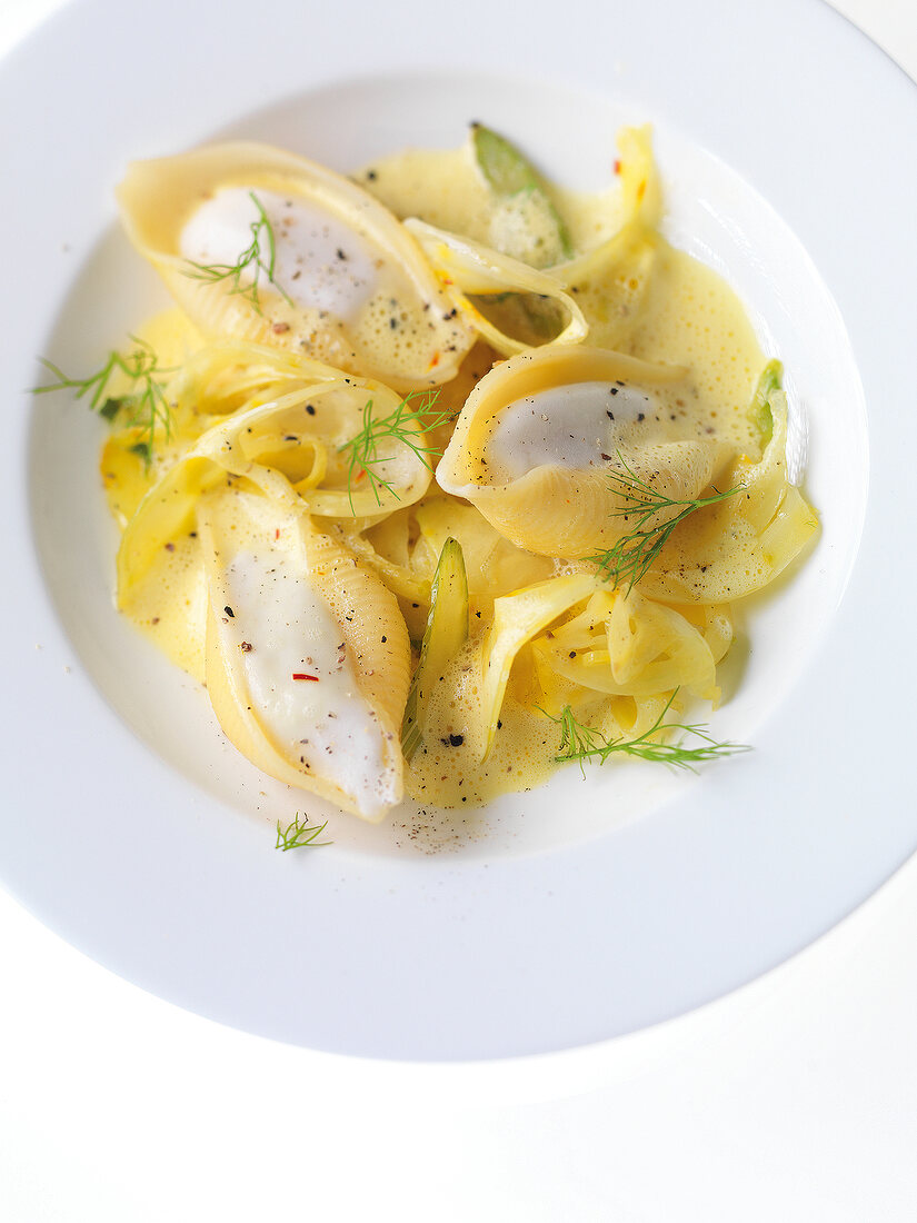 Close-up of stuffed pasta shells with fennel, saffron and vegetables on plate