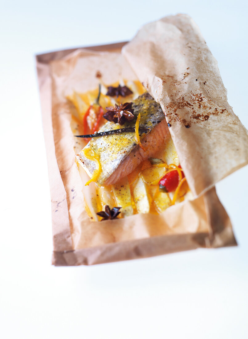 Close-up of salmon with asparagus and orange-spice butter in baking paper