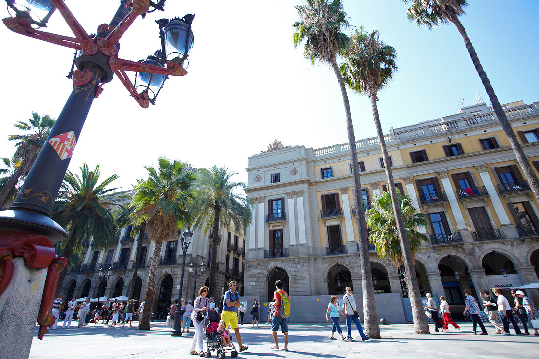 Tourists on Placa Reial with palm trees and street lantern, Barcelona, Spain