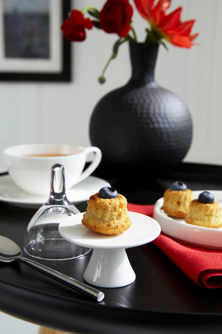 Muffins mit Heidelbeeren,Tee auf Tisch in schwarz, schwarze Vase