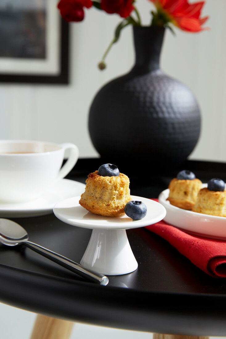 Muffins mit Heidelbeeren,Tee auf Tisch in schwarz, schwarze Vase