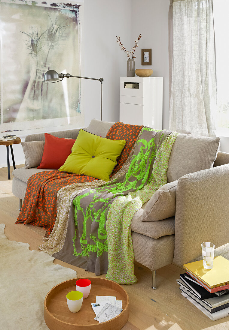 Colourful clothes lying on beige sofa