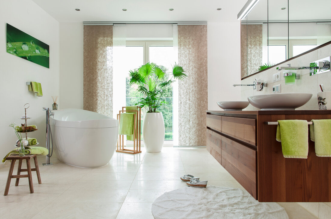 Bad mit ovaler Badewanne, Waschtisch aus Akazienholz, grüne Accessoires
