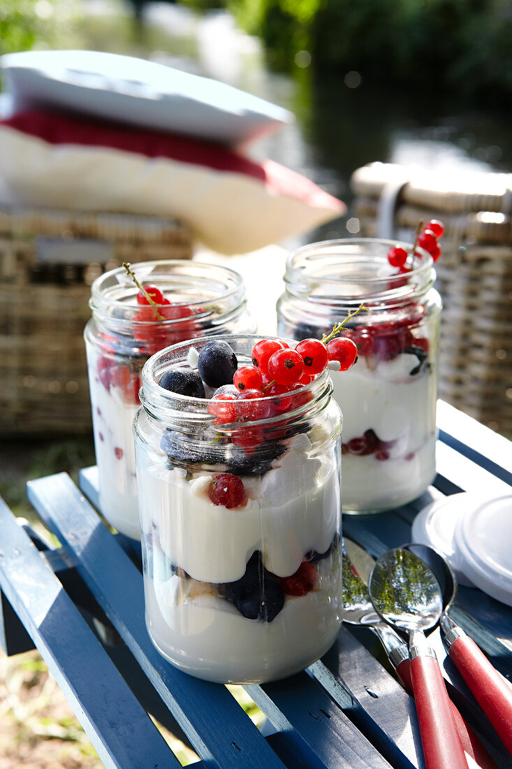 Jar of junket with berries on picnic table