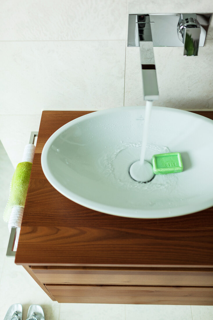 Green soap in oval sink with running faucet