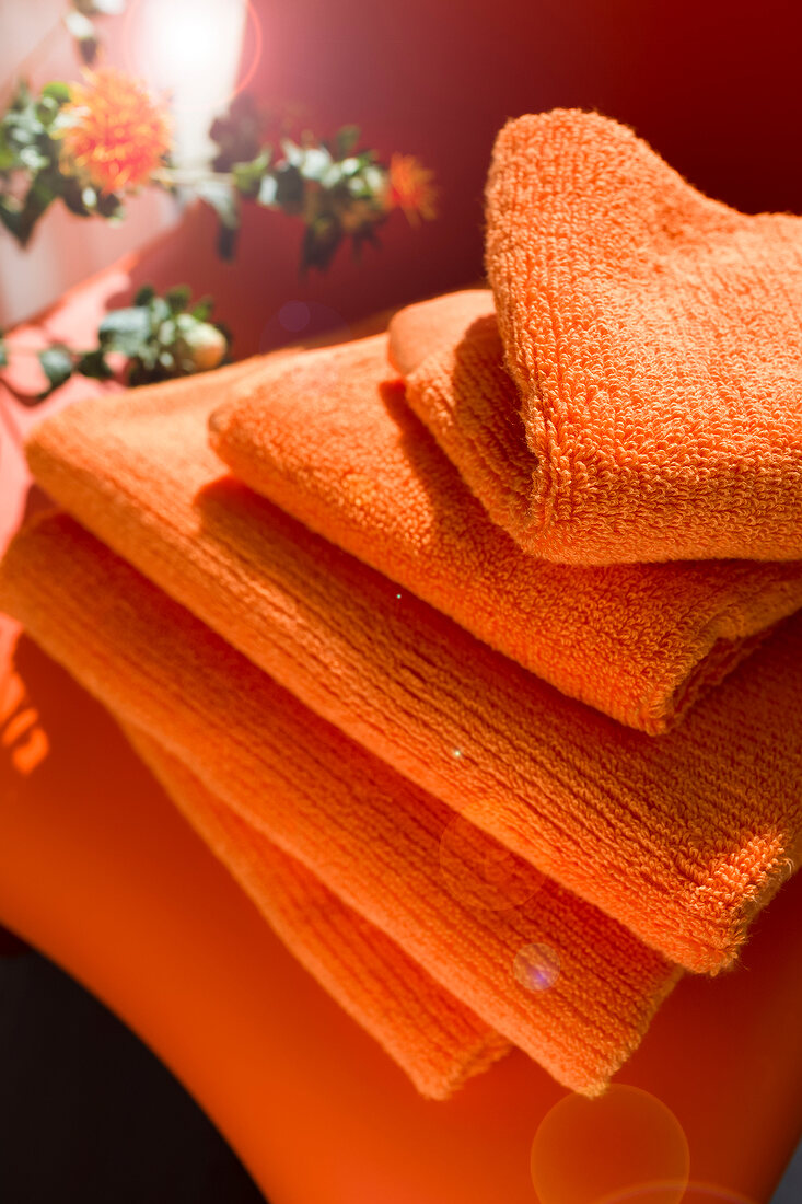 Stack of orange coloured towels in bathroom