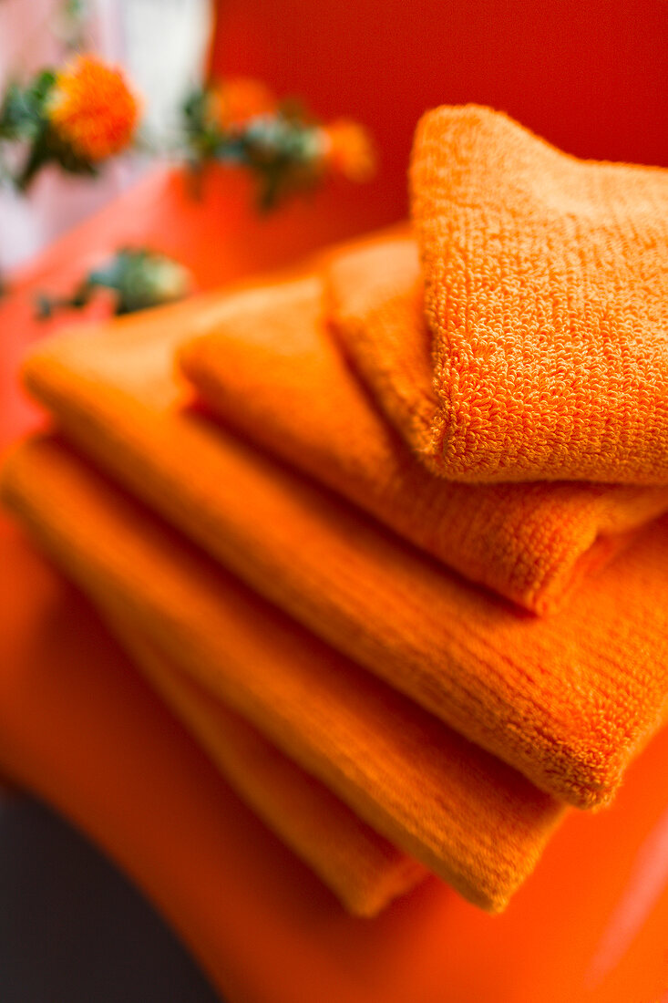 Stack of orange coloured towels in bathroom