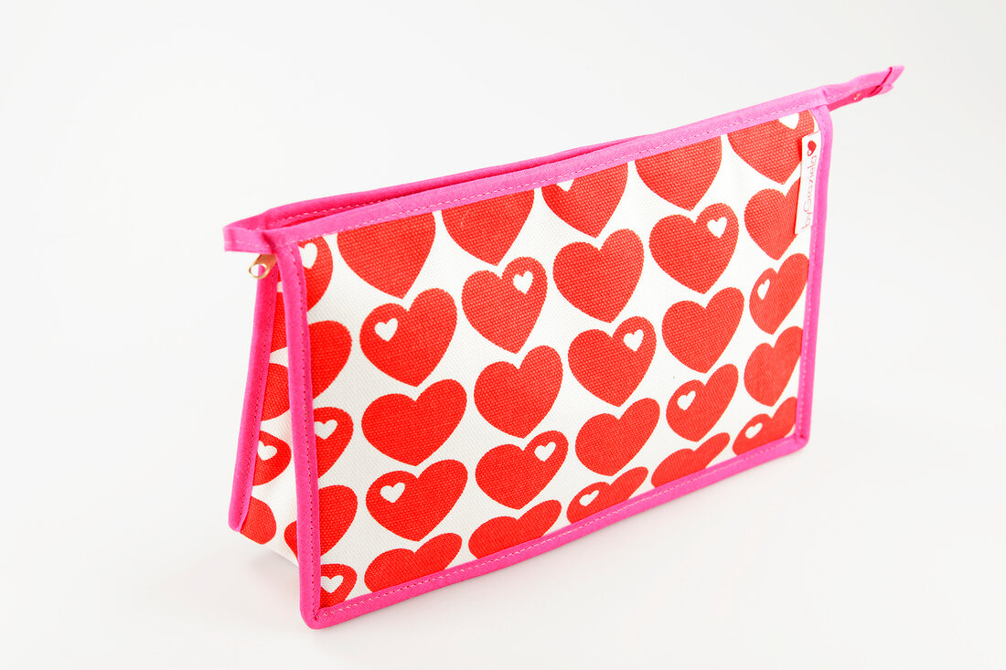 Red and white cosmetic pouch with hearts and pink trim on white background