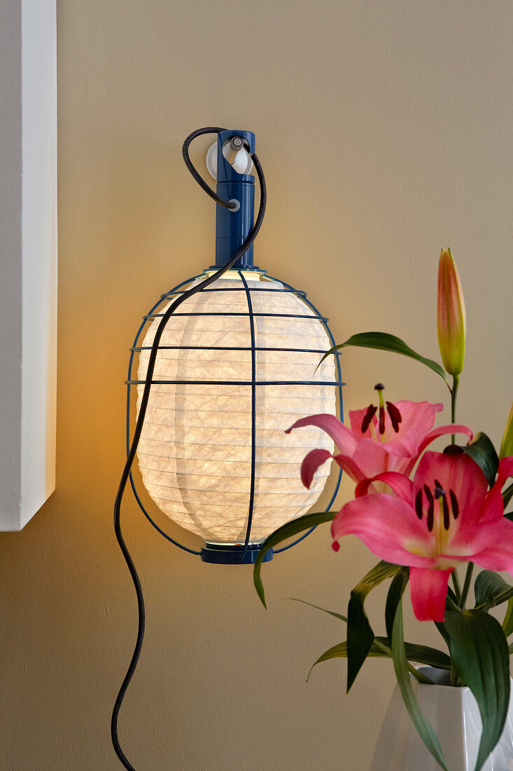 Close-up of portable lamp with paper shade and flower vase