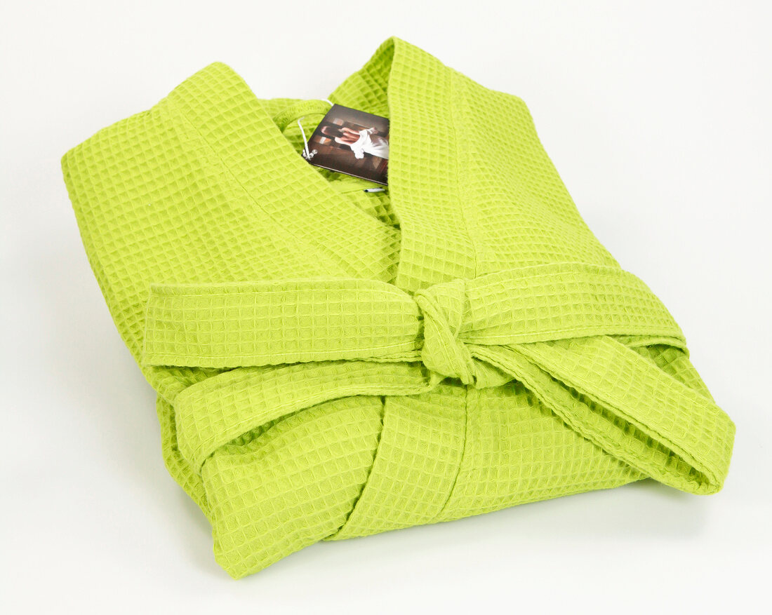 Folded green robe with knotted belt on white background