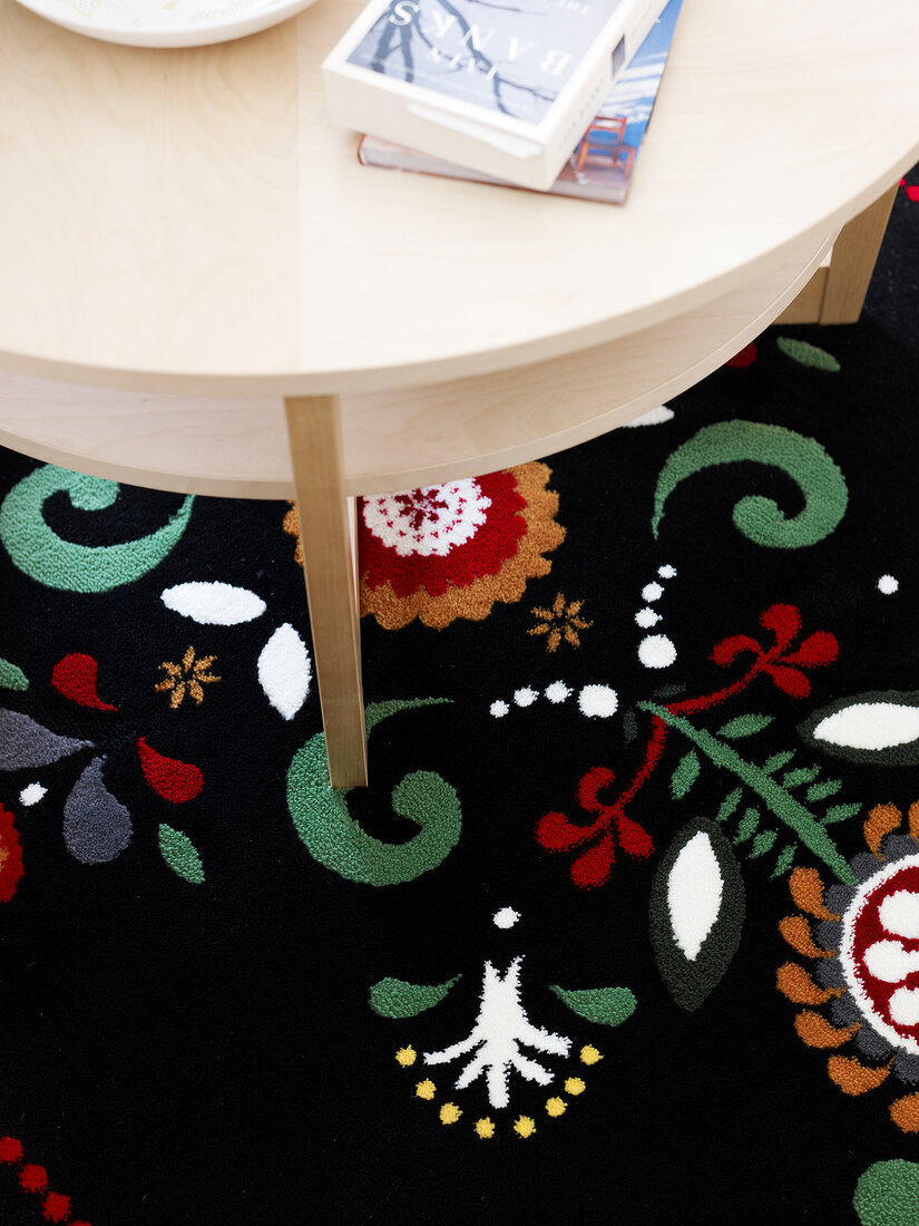 schwarzer Teppich mit buntem Muster, runder Tisch