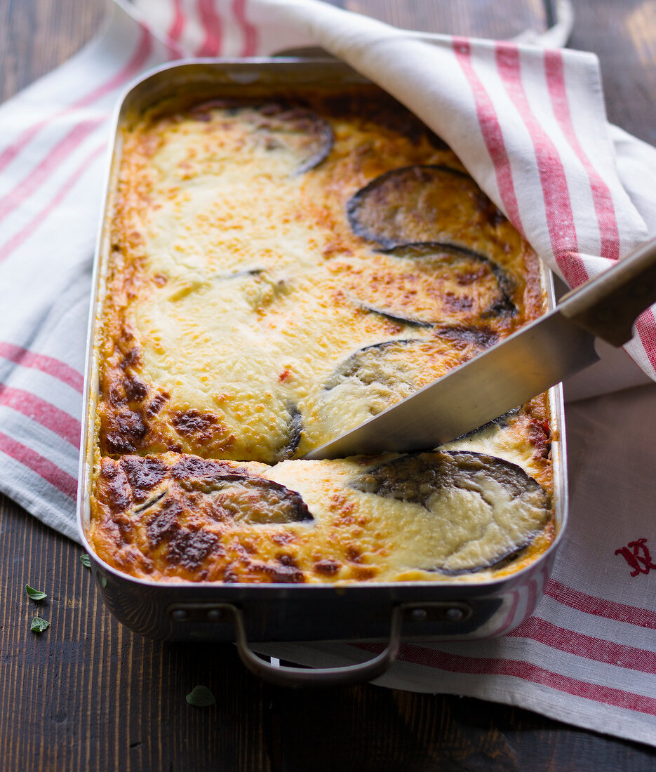 Moussaka with knife in steel baking dish