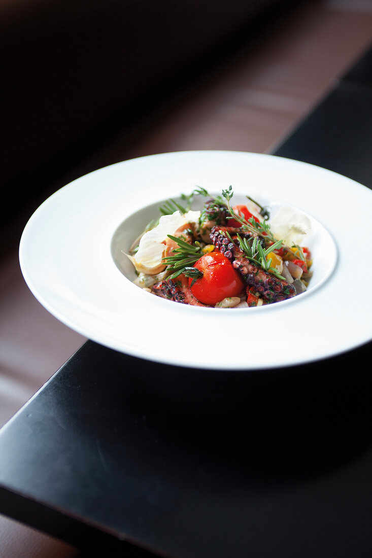 Octopus with tomato salad and rosemary on plate