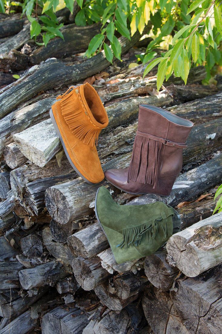Three fringed suede boots on wooden logs