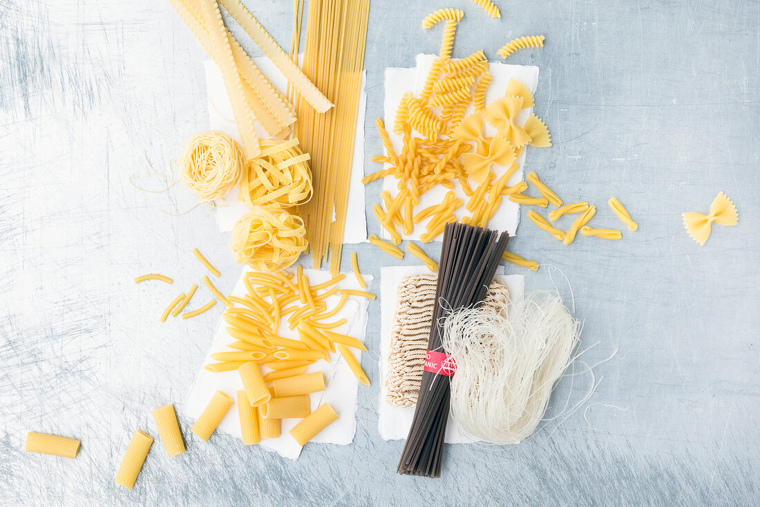 Various types of raw pasta on gray background