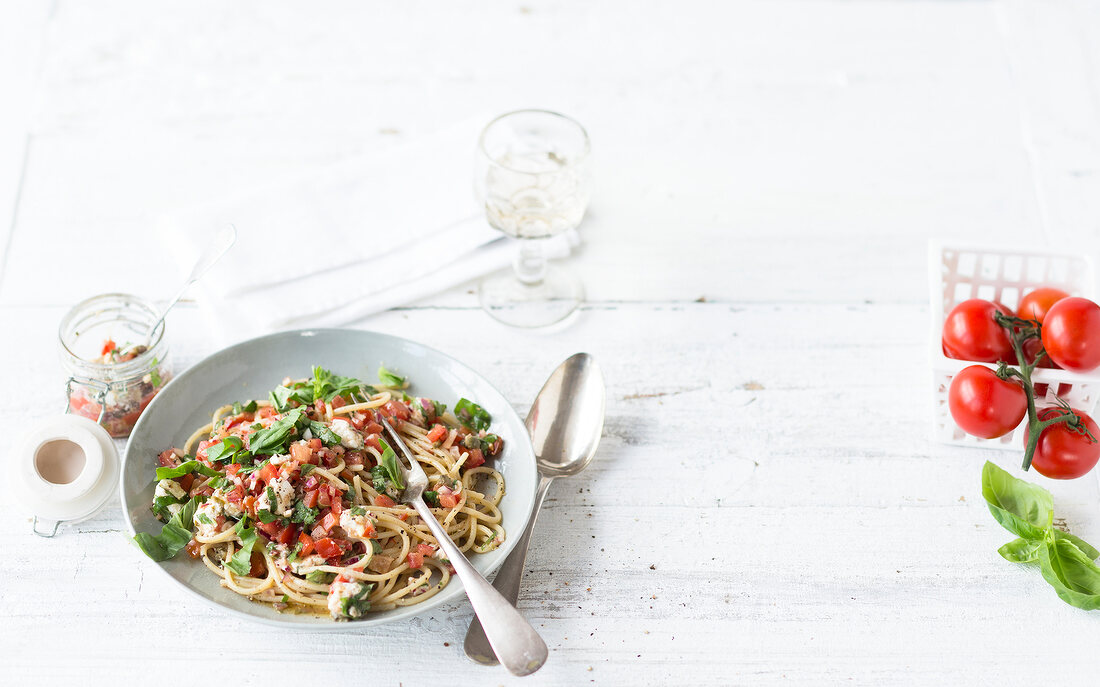 Spaghetti with tomato, goat cheese and salsa on plate