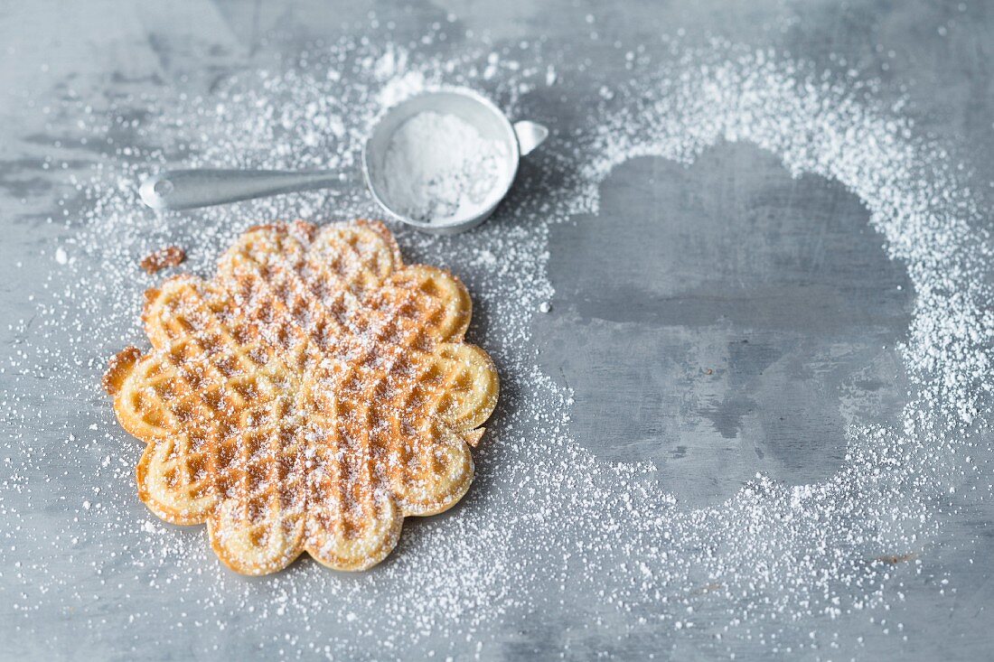 A freshly baked waffle with icing sugar