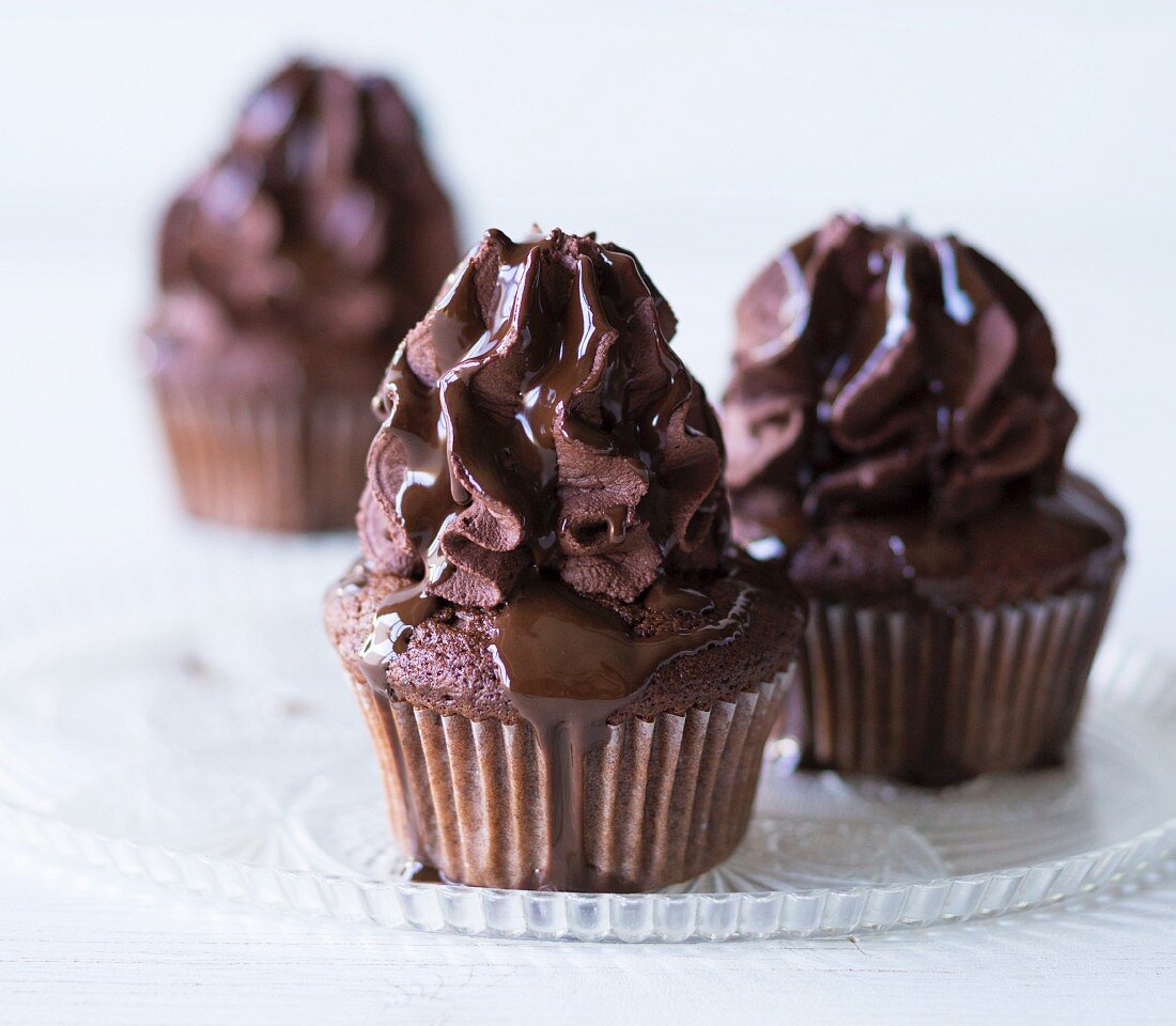 Chocolate cupcakes topped with chocolate cream and chocolate sauce